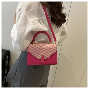 Detail showing fuchsia handbag with gold lock and woven texture on shoulder of model