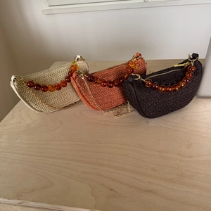 Three half-moon straw handbags with amber bead handles and metal chains for summer