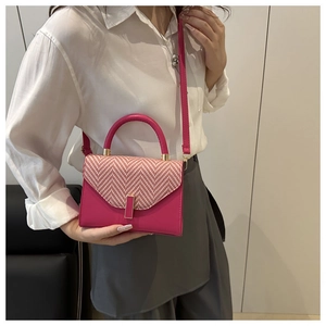 Detail of pink woven texture handbag with golden clasp shown on a model