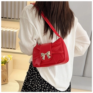 Detalle de un bolso de mano rojo con un gran lazo y hebilla metálica dorada brillante