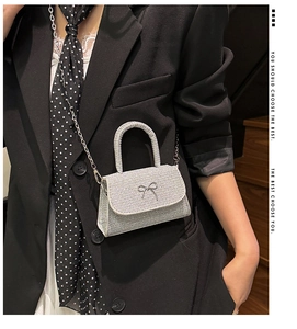 Detail of silver rhinestone mini handbag with a crystal bow and metallic chain