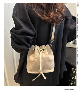 Macro shot of minimalist beige bucket bag with drawstring closure and golden eyelets