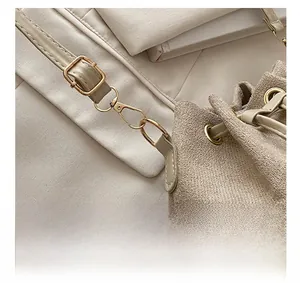 Close-up of golden hardware accents and matte suede texture on beige bucket bag