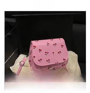 Close-up of pink cherry print saddle bag inside a gift box with silver metal buckle
