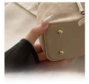 Detail of beige mini bucket bag base with golden studs and precision stitching