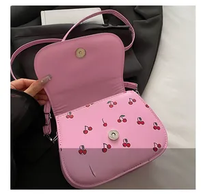 Close-up of pink saddle bag interior featuring cherry print and silver magnetic buckle