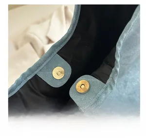Close-up of golden magnetic snap button on light blue textured tote bag interior
