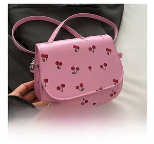 Close-up of pink leather saddle bag with cherry print and silver metal hook