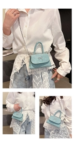 Macro detail of glossy light blue square bag with metal bow and silver chain strap
