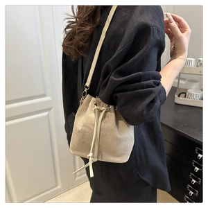 Detail of minimalist drawstring bucket bag in beige matte texture with thin shoulder strap