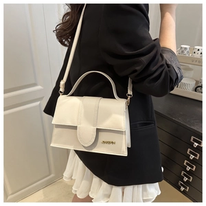 Detalle de bolso crema con correa ajustable y logotipo metálico dorado elegante