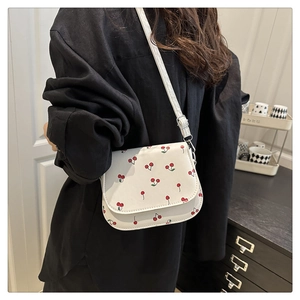 Detailed view of the red cherry print on white PU leather saddle bag with chain