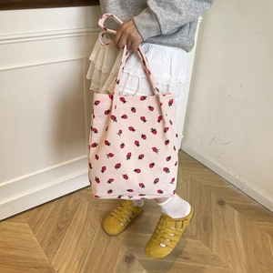 Dettaglio della borsa tote in velluto a coste rosa con motivi a fragola e due manici
