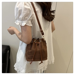 Sac seau marron en suédine porté avec une robe blanche pour un look d'été élégant