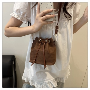 Detail of vintage brown drawstring bucket bag featuring matte suede texture and gold metal rings