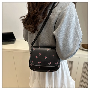 Model wearing a black cherry print saddle bag with stylish chain strap and casual outfit