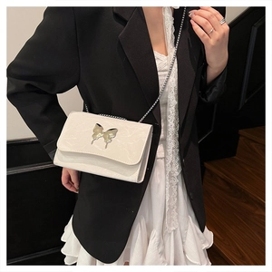 Detail van de witte crossbodytas met textuur en een grote zilveren vlinder metalen gesp