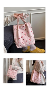 Dettaglio della borsa tote in velluto rosa con motivi a ciliegia e manici