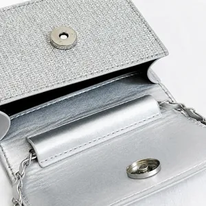 Dettaglio della borsa a catena argento con chiusura magnetica e texture di paillettes