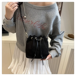 Close-up of black matte bucket bag featuring a metal ring and drawstring closure system