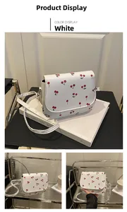 Detail view of white cherry print saddle bag with chain strap and flap closure
