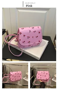Close-up of pink saddle bag with cherry print, smooth leather texture and metal chain strap