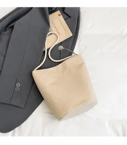 Détail du cabas beige montrant le grain de cuir litchi et la bandoulière en corde tissée