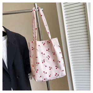 Dettaglio della borsa tote in velluto rosa con ricami a ciliegia su una gruccia