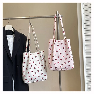 Dettaglio delle borse tote in velluto a coste bianco e rosa con motivi a fragola