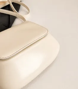 Detail view of the lightweight cream leather saddle bag showing flap and strap texture