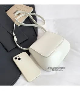 Creamy white saddle bag size comparison with a smartphone on an elegant background