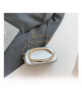 Détail du sac de soirée argenté avec poignée dorée et chaîne sur tissu de costume