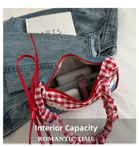 Interior view of denim handbag with red gingham handle showing capacity for phone and cosmetics