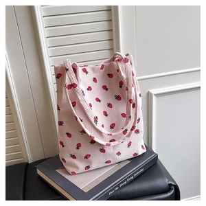 Dettaglio di borsa tote in velluto a coste rosa con motivi a fragola e texture soffice