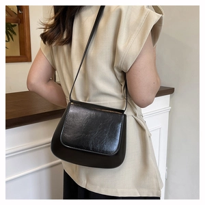 Close-up of black PU leather saddle bag showing the glossy texture and sleek flap design