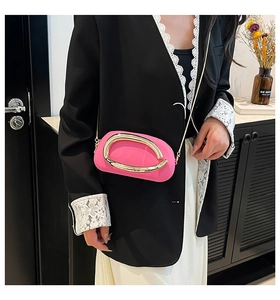 Détail du sac bandoulière rose vif avec grande poignée en U dorée et fine chaîne métal
