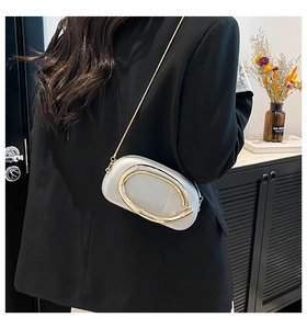 Détail de pochette en acrylique blanc avec boucle C dorée sur costume noir