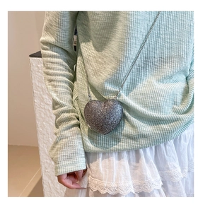 Détail d'un sac de soirée en forme de cœur avec paillettes argentées et fine chaîne en métal
