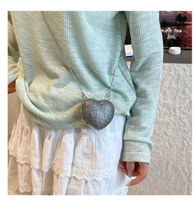 Silver sequin heart-shaped crossbody bag with metal chain shown on model