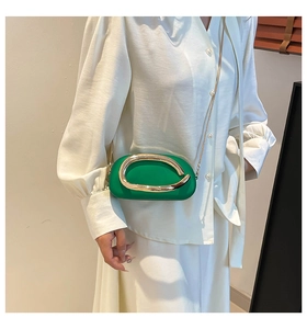 Détail d'un sac de soirée capsule vert avec garniture dorée porté par un modèle