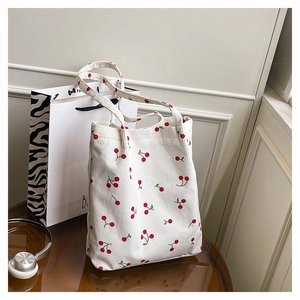 Dettaglio della borsa tote in velluto bianco con ricamo di ciliegie rosse e trama morbida