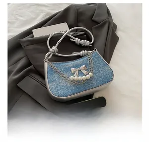 Detail of blue tweed shoulder bag with silver butterfly charm and chain strap