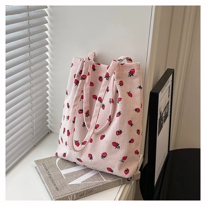 Dettaglio della borsa tote in velluto a coste rosa con stampe di fragole rosse