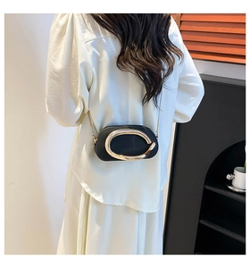 Détail d'un sac bandoulière vintage en cuir noir avec un fermoir ovale doré et une chaîne