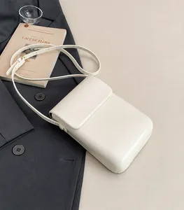 Vista detallada de un bolso bandolera blanco minimalista de cuero para teléfono móvil