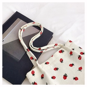 Dettaglio della stampa a fragola sulla borsa tote in velluto a coste bianco crema