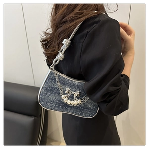 Détail du sac en jean avec boucle papillon et bandoulière à nœuds argentés