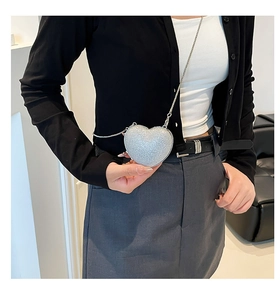 Detail of silver heart-shaped mini bag with sparkling sequins and slim metal chain strap