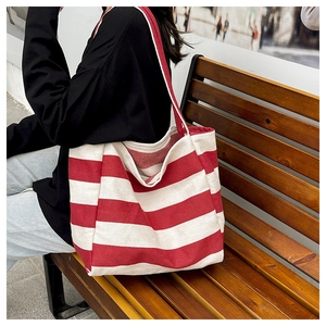 Detailopname van dikke canvastextuur op de grote rood-wit gestreepte shopper tas