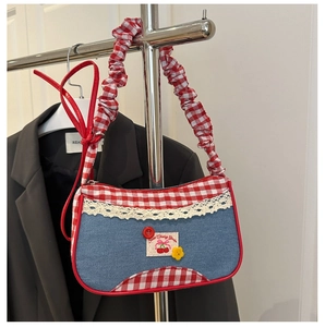 Detail of denim handbag with red plaid trim, lace borders, and cherry embroidery charm